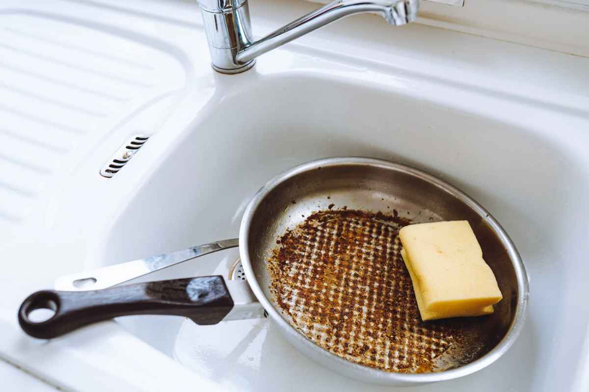 Padella bruciata con spugna nel lavandino