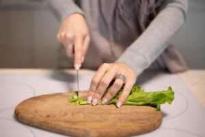 Donna che taglia insalata su un tagliere