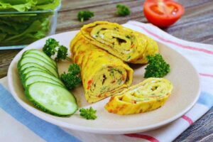 un rotolo di frittata con verdure e un cetriolo a fette